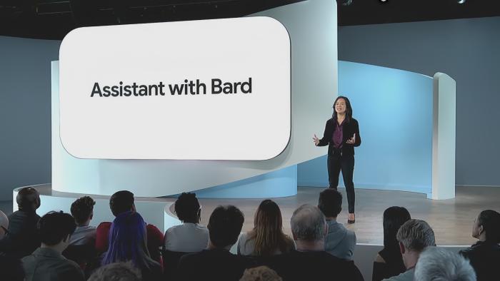 A Google presenter onstage with a slide reading "Google Assistant with Bard"