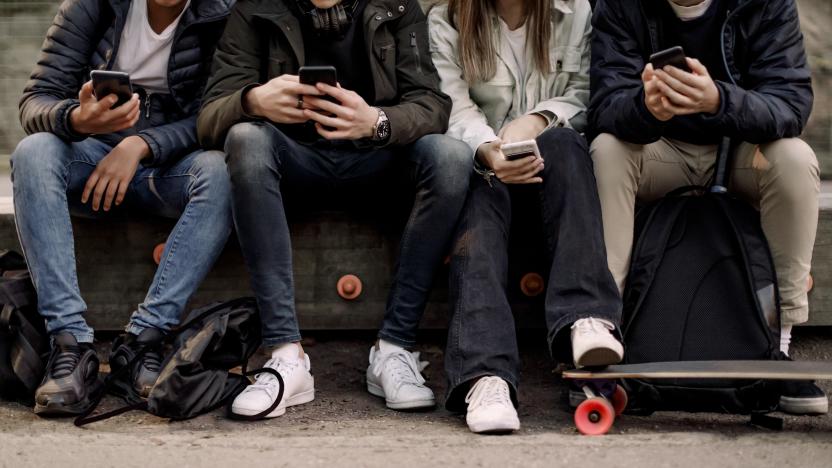 Low section of teenage boys and girl using smart phone while sitting at park