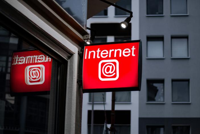 A red sign hanging outside a building. It reads "Internet" and includes an "at" symbol.