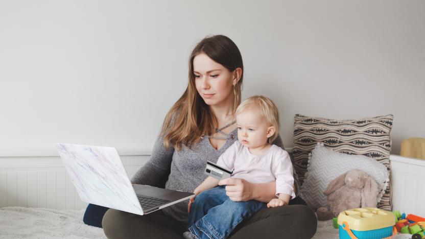 Young Caucasian mother with baby shopping online from home. Stay at home single mom with kid toddler daughter buying ordering products food on Internet and paying with credit card.