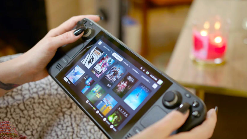 A cropped image showing someone holding a Valve Steam Deck handheld gaming console in their lap while on a living room couch.