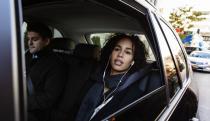 Two Uber passengers listen to headphones as they sit in the back of a black car in NYC.