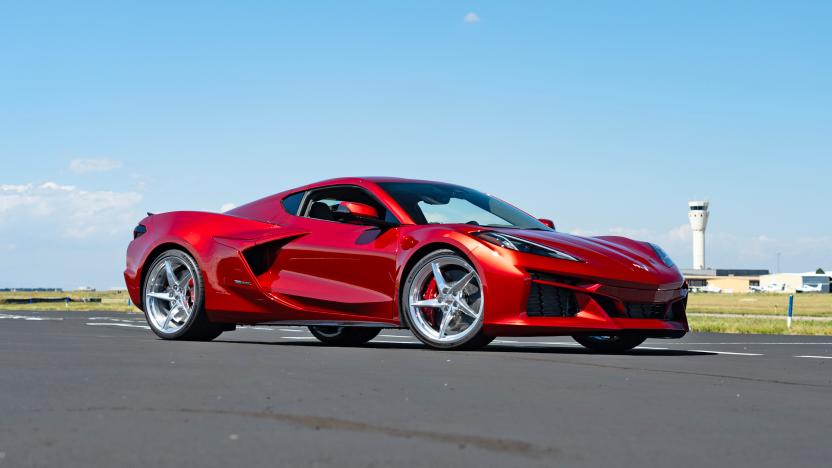 A burgundy Chevrolet Corvette E-Ray sits on what appears to be an airport runway.
