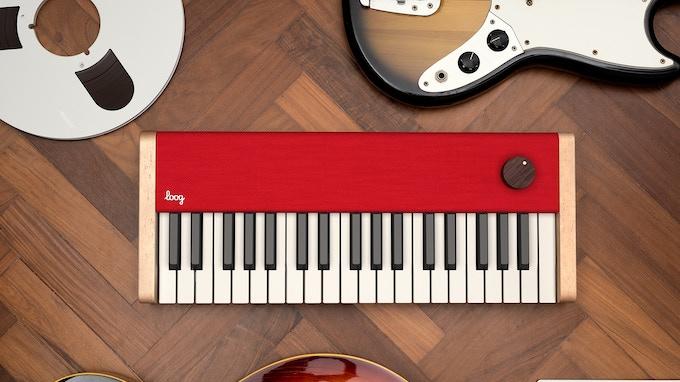 An image of Loog's Piano surrounded by guitars and tape reels. 