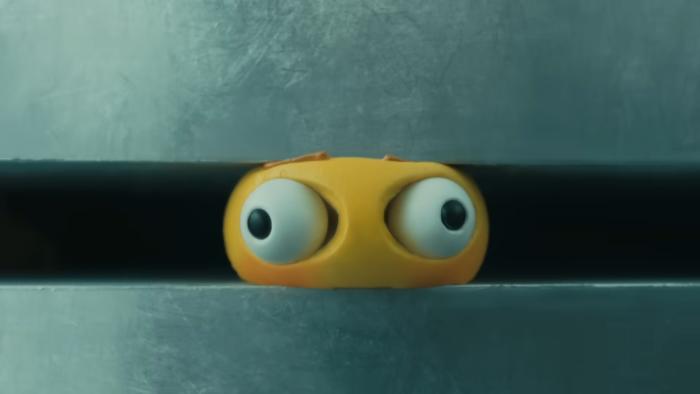 A yellow emoji being crushed in an industrial crusher. Its eyes bulge out of its head.
